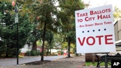 A sidewalk sign directs voters where to go in front of the library in Lake Oswego, Ore., Oct. 31, 2018.