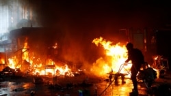 在香港理工大学学生与警察的冲突中一名抗议者试图浇灭火焰。（2019年11月18日）