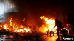 在香港理工大学学生与警察的冲突中一名抗议者试图浇灭火焰。（2019年11月18日）