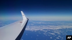 A protester wearing a Guy Fawkes mask stands among a group of protesters from tobacconist groups throwing papers in the air in oppostion to neutral cigarette packaging in Paris, France. Government officials claim the packaging will help to reduce the attractiveness of the product, while the tobacco industry claims plain packing will permit easier means of producing counterfeit cigarettes.