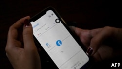 一名婦女使用手機在仰光查看Facebook，緬甸將軍在奪權數天后下令互聯網提供商限制訪問Facebook。（2021年2月4日） （STR /法新社） 