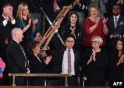 川普总统国情咨文演说特邀嘉宾池成镐在川普演说中提到他时站起身来挥舞拐杖致意。（2018年1月30日）