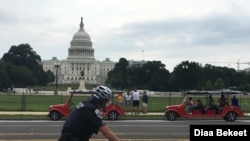Tourists stand in front of the U.S. Capitol in Washington, DC, on an unusually warm day, with highs into the upper 80s fahrenheit in some areas, Thursday, July 18, 2019. (Photo by Diaa Bekheet)