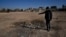 FILE - A man shows a crater where a surface-to-surface missile loaded with sarin struck, during a 2013 chemical weapons attack that was blamed on then President Bashar al-Assad's forces, on the outskirts of Damascus, Syria, Dec. 25, 2024.