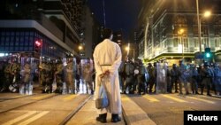 在香港堅尼地城，一名宗教人士站在防暴警察前。(2019年8月4日)