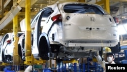 戴口罩的工人在武汉的东风集团本田汽车公司的一条生产线上工作。（2020年3月16日）