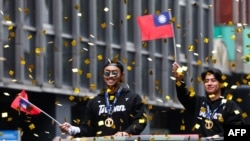 資料照：2024年11月26日，在台北，台灣棒球隊隊長陳傑憲(右)和球員林家正在慶祝球隊贏得2024WBSC十二強棒球錦標賽冠軍的遊行中向人群揮手致意。 （法新社）