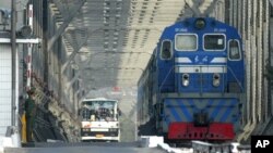 资料照- 一名中国武警卫兵注视着经朝中边境的友谊桥从朝鲜一方驶入中国丹东市的客运火车和大巴。
