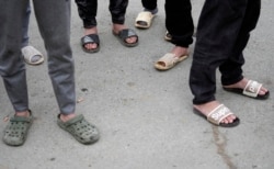 塞爾維亞北部城鎮茲雷尼亞寧附近一家中國汽車輪胎工廠建築工地工作的越南工人光著腳站在工房前 （2021年11月18日）