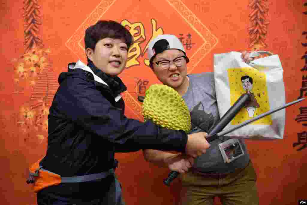 旺角花墟年宵市場檔主江小姐（右）與拍擋拿著雨傘運動的道具拍賀年照。（美國之音湯惠芸攝）