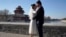 FILE - Groom Dong Yangfeng and bride Wang Sai pose for photos near the Forbidden City in Beijing on Dec. 20, 2020. 