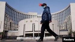 一名戴著口罩的男子走過北京的中國人民銀行總部。（2020年2月3日）