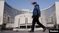 一名戴著口罩的男子走過北京的中國人民銀行總部。（2020年2月3日）