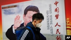 北京街道上，戴口罩的行人走过带有中国领导人习近平像的海报，海报上有标语“中国梦人民的梦”（2017年10月26日）