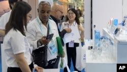  2023年11月4日廣州進出口商品交易會上，參展商在推廣保健設備的展位上接待外國參觀者。