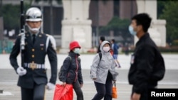 資料照片--遊客在經過台北中正紀念館的升旗儀式時，戴上防護口罩以保護自己免受冠狀病毒病(冠狀病毒)的侵襲。 （2020年3月11日）