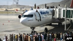 在喀布尔机场，人们争先恐后地爬上飞机顶部，等待离开喀布尔。（2021年8月16日）