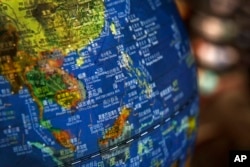 ໃນພາບນີ້ ເມື່ອວັນທີ 13 ກໍລະກົດ 2018, ແຜນທີ່ຮູບໜ່ວຍໂລກ ສະແດງໃຫ້ເຫັນເກາະດອນຕ່າງໆ ຢູ່ໃນທະເລຈີນໃຕ້ ພ້ອມດ້ວຍເສັ້ນຂີດ ເກົ້າເສັ້ນ ທີ່ຈີນອ້າງວ່າ ຢູ່ພາຍໃຕ້ເຂດແດນຂອງຕົນ, ຊຶ່ງວາງສະແດງຢູ່ທີ່ຮ້ານຂາຍປຶ້ມ ໃນນະຄອນຫຼວງປັກກິ່ງ.