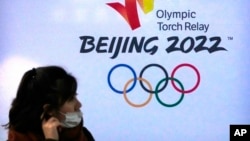 一名女子走過北京冬奧會的大幅廣告。（2021年12月9日）