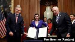 眾議院議長佩洛西(中)展示價值2.2萬億美元的新型冠狀病毒援助法案（2020年3月27日）。