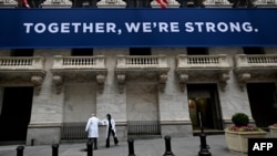 纽约证券交易所开市前，医护人员抵达时用手肘相互致意。在关闭了两个月之后，纽约证券交易所对交易员重新开放（2020年5月26日）。