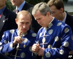 2001年10月21日 ，俄罗斯总统弗拉基米尔·普京和美国总统乔治·布什穿着中国传统丝绸外衣，在亚太经济合作组织（APEC）上海峰会上参加全家福合影时交谈。