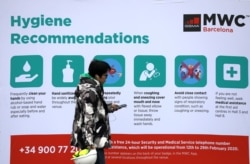 一名男子走过西班牙巴塞罗那世界移动大会的保持个人卫生的相关信息。（2020年2月12日）