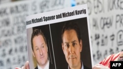  加拿大抗議人士舉著加拿大商人邁克爾·斯帕弗（Michael Spavor）和加拿大前外交官康明凱（Michael Kovrig）的頭像的標語，抗議中國政府任意拘押這兩位加拿大公民。（美聯社）