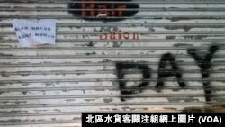 上水一間店舖落閘暫停營業，鐵閘上貼上反對反水貨客示威的標語。(北區水貨客關注組網上圖片)
