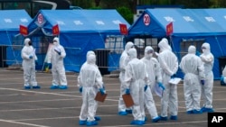 資料照：身穿大白防護衣的人負責將來自武漢的人周轉到北京某處隔離地點。 （2020年4月15日）