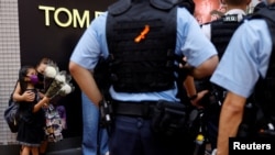 香港警察在街頭制止一對持花母女悼念一位刺傷警察後自殺身亡的男子。 (2021年7月2日)