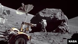 แฮร์ริสัน ชมิทท์ ถูกบันทึกภาพระหว่างยืนอยู่ข้าง ถัดจากก้อนหินขนาดใหญ่ ที่สถานี 6 บนฐานลาดเอียงของนอร์ธแมสซีฟ ระหว่างกิจกรรมนอกยานพาหนะอพอลโล 17 ครั้งที่ 3 (EVA-3) บริเวณทอรัส-ลิตโทรว แลนด์ดิง ไซต์ (องค์การนาซา)