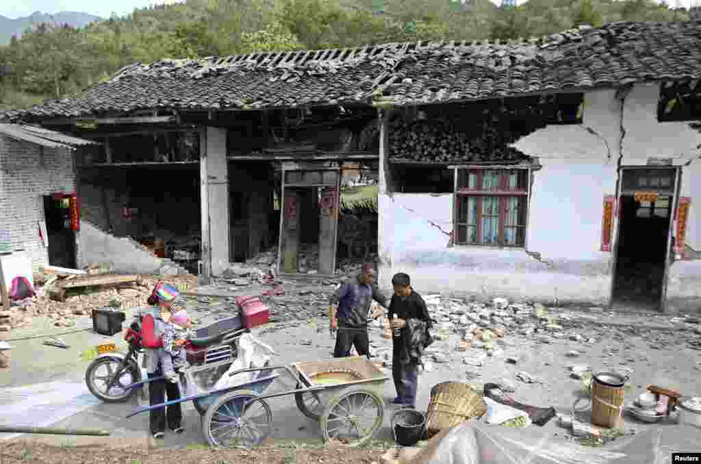2013年4月20日星期六，中国四川省雅安市芦山县发生里氏7级强烈地震。在龙门乡人们站在被震毁的房屋外面。