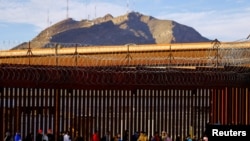 2023年1月5日，移民越过里约布拉沃河后，在美墨边境围栏附近排队申请庇护。（路透社照片）