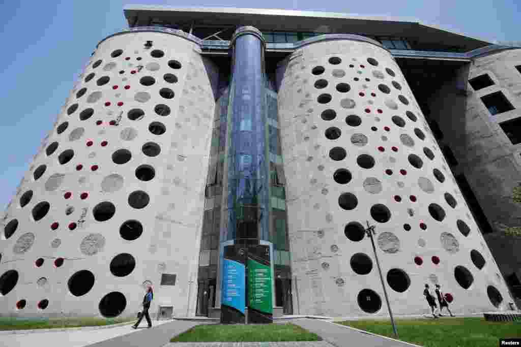 2018年6月4日，在2022年冬季奥运会和残奥会北京组委会总部办公大楼前，工作人员走过。