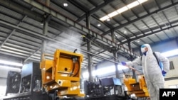 中国江苏省连云港市的一名工人在给工厂的机器喷洒消毒药水为工人节后返工做准备。（2020年2月9日）