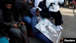 ຍິງສາາວຄົນນຶ່ງ ພະຍາຍາມເຮັກໃຫ້ຕົນເອງອົບອຸ່ນ ໃນຂະນະທີ່ນາງຖືແຜ່ນພາບຂອງ ທ່ານ ຄິງ ໃນລະຫວ່າງວັນບຸນ Martin Luther King Jr. ໃນເມືອງໂຄລອມເບຍ, ລັດຄາໂຣໄລນາໃຕ້, ວັນທີ 20 ມັງກອນ 2020.