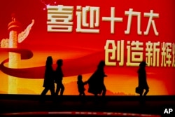 北京居民走過迎接中共十九大召開的大型電子屏幕（2017年10月15日）