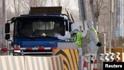 身穿防护服的警察在河北省通往北京的一个道路检查站拦住一辆卡车。（资料照， 2021年1月12日）