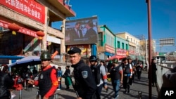 一名中國警察帶領一隊武裝民兵在新疆和田的市場外巡邏。（2017年11月3日） 