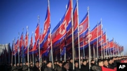 朝鲜人手举国旗在平壤金日成广场游行向朝鲜劳动党表忠诚.(2016年2月25日)