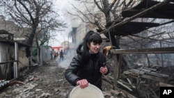 俄烏戰爭開戰的第一天，烏克蘭馬里烏波爾的一名婦女逃竄經過俄羅斯炮擊後的廢墟。(美聯社：2022年2月24日)