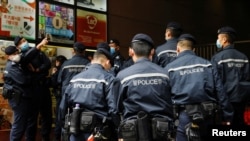 香港警察在逮捕《立场新闻》六名高管后站在该港媒办公楼外。（资料照，2021年12月19日）