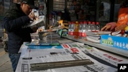 一位男士在北京一處報攤瀏覽譴責加拿大應美國要求拘捕華為高管孟晚舟的中國報刊。(2018年12月10日)