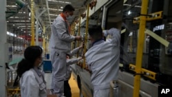 资料照：中国湖北省一个工厂的工人正在组装小巴。（美联社2023年5月10日）