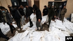 2023年12月25日，在加沙走廊南部代爾巴拉赫的阿克薩醫院舉行集體葬禮之前，醫務人員和志工擺放的在以色列襲擊馬加齊難民營時喪生人員的屍體。 （法新社照片）