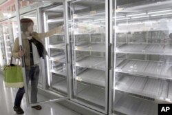 一女士从东京某便利店几乎空掉的货柜里拿出一瓶果汁