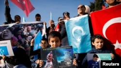 在土耳其伊斯坦布尔一个反对中国的抗议活动中，几个维吾尔族少年举着印有英国足球俱乐部阿森纳球星梅苏特照片的海报。(2019年12月14日)