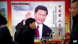 資料照片：北京街頭人們走過一個有著習近平肖像，並寫著“中國夢，人民的夢”的廣告看板。 （2018年3月2日）