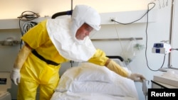 2014年10月15日，瑞士巴塞尔医院的一名感染控制护士穿着防护服向媒体介绍埃博拉病人使用的隔离病房。